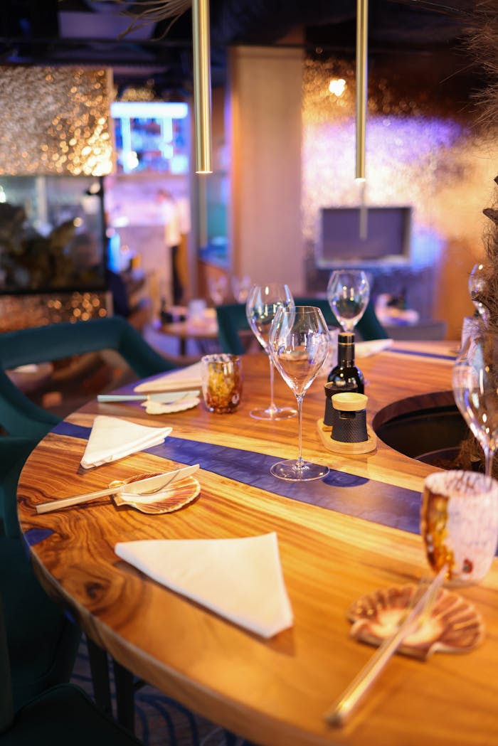 A stylish dining table setting with wine glasses and napkins in a cozy restaurant ambiance.